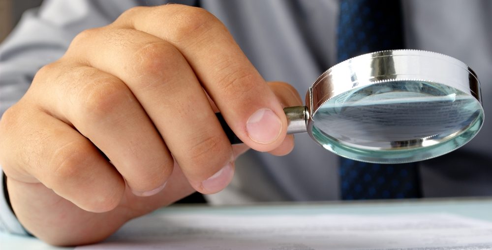 Businessman looking through a magnifying glass to documents